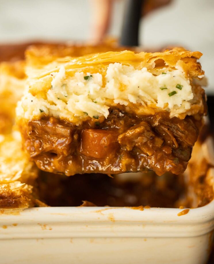 close up shot of spatula lifting portion of steak and guinness pie from baking dish