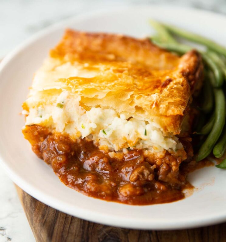 portion of steak and guinness pie on small white plate with green beans