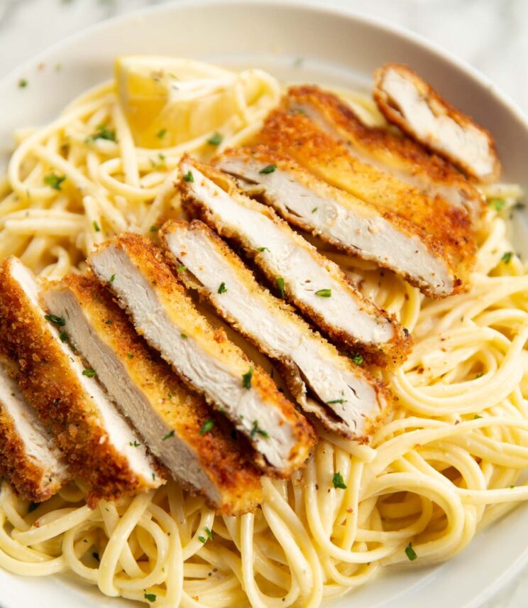 sliced crispy chicken served on pasta in large white bowl