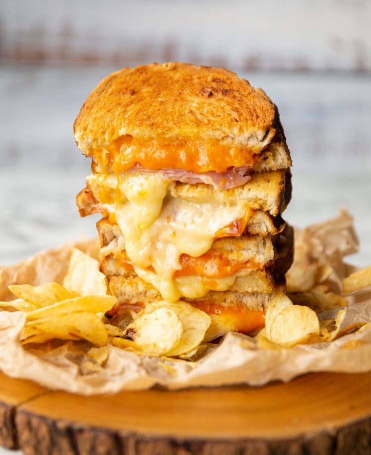 air fryer ham cheese toastie on wooden board with crisps