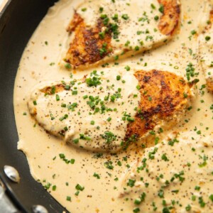 cream cheese chicken in large pan garnished with chives and black pepper