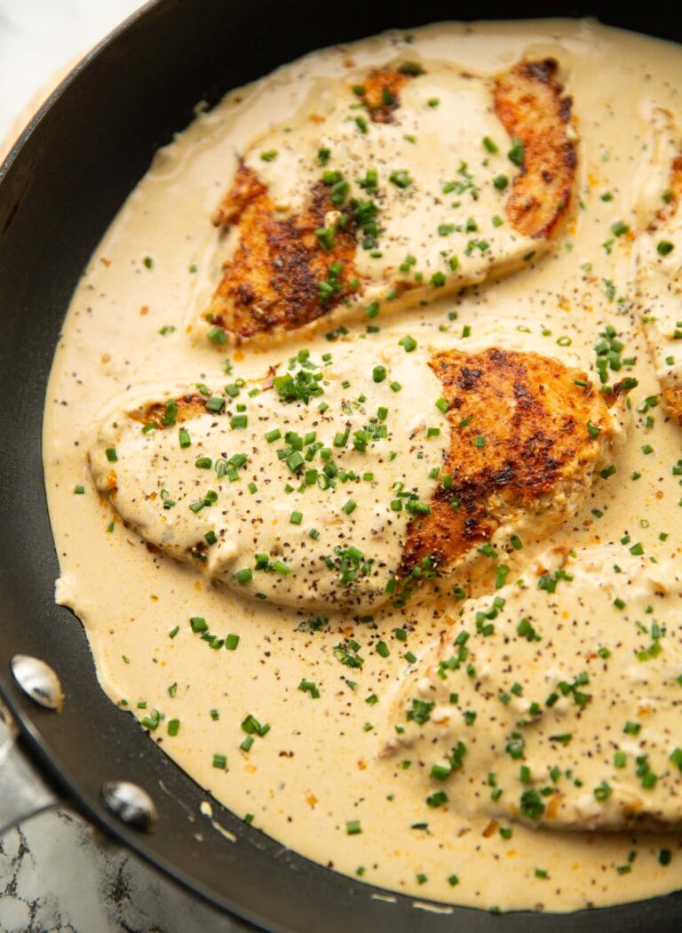 cream cheese chicken in large pan garnished with chives and black pepper