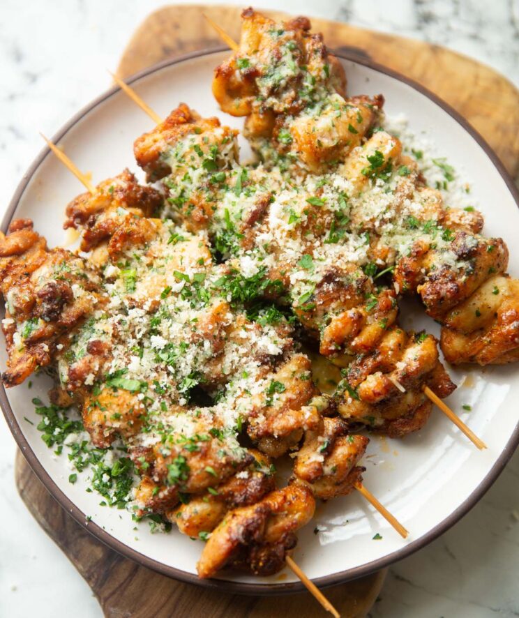 four air fryer garlic parmesan chicken skewers on small white plate