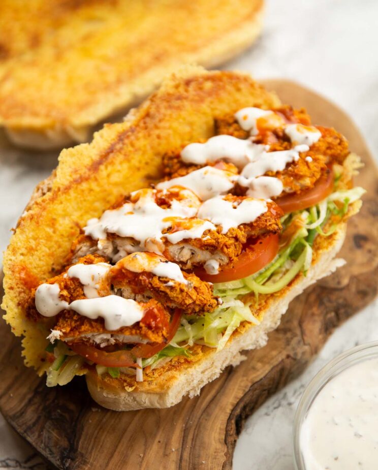 close up shot of chicken tender sandwich on wooden board showing filling