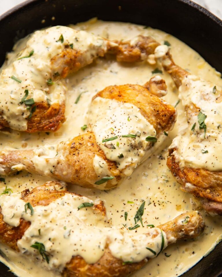 creamy mustard chicken served in large cast-iron pan garnished with tarragon