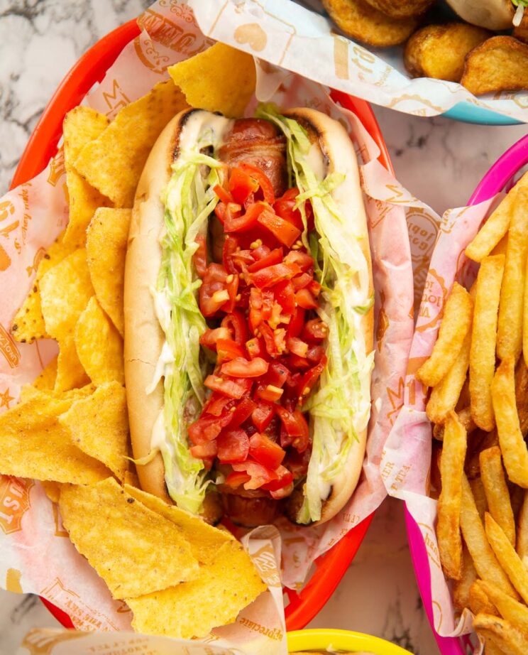 blt hot dog served with tortilla chips in red basket