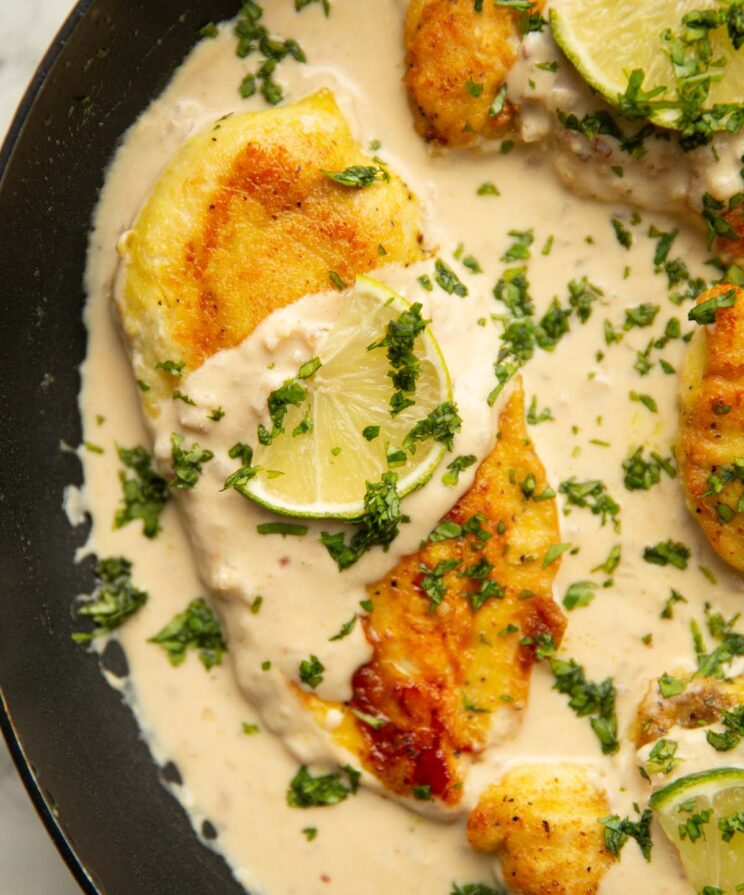 close up overhead shot of coconut lime chicken in pan garnished with lime and coriander