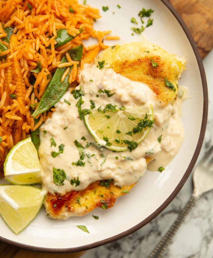 coconut lime chicken served on small white plate with lime, coriander and rice