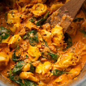 sausage tortellini in large pot with wooden spoon digging in