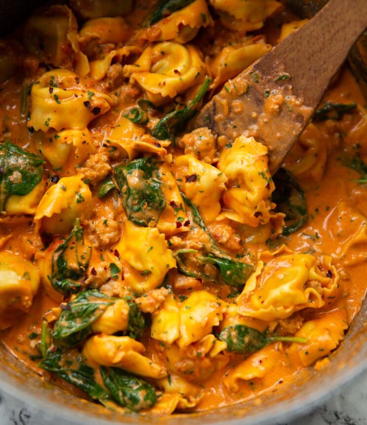 sausage tortellini in large pot with wooden spoon digging in