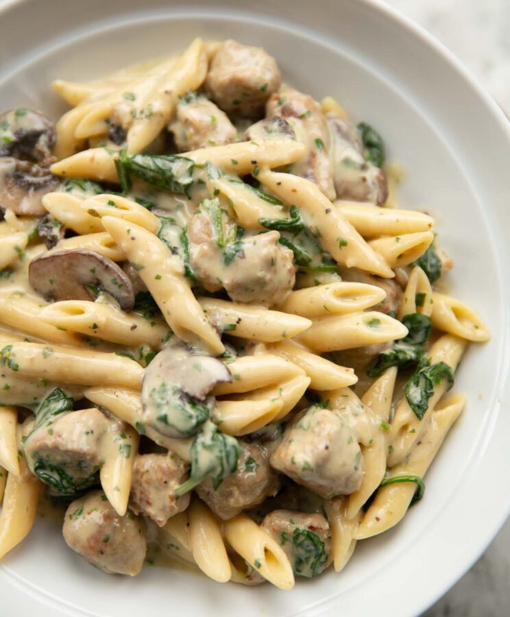 close up shot of sausage and mushroom pasta in large white bowl
