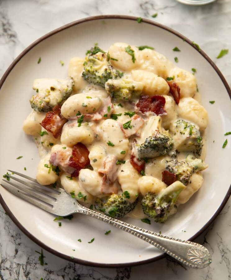 bacon boursin broccoli gnocchi on small white plate with silver fork
