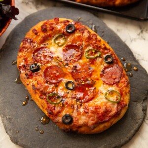 garlic flatbread pizza on slate drizzled with hot honey