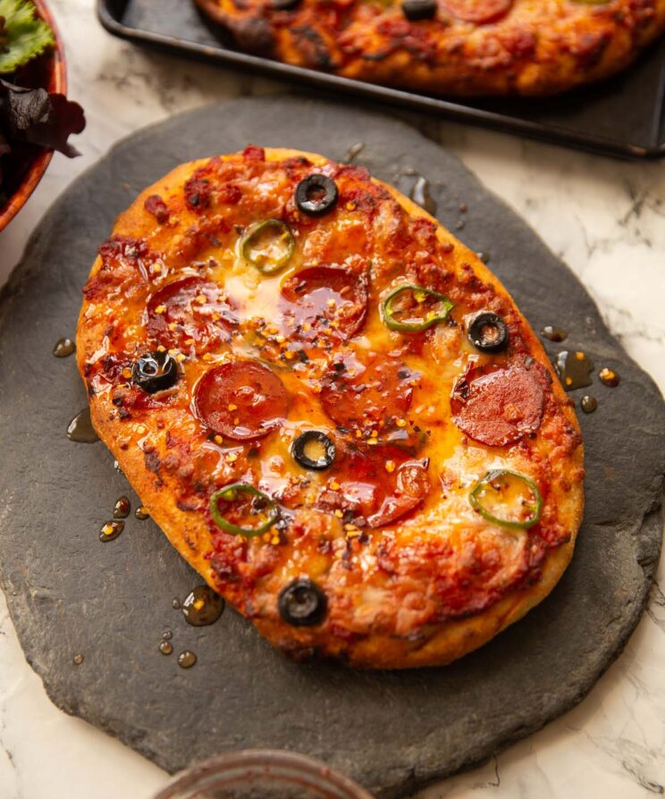 garlic flatbread pizza on slate drizzled with hot honey