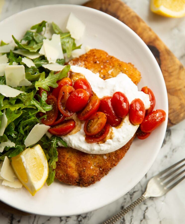 burrata chicken milanese on small white plate with salad