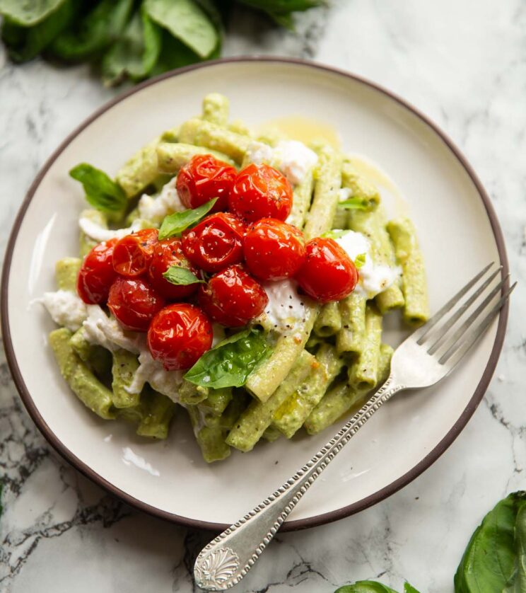 creamy pistachio pesto pasta on small white plate with silver fork