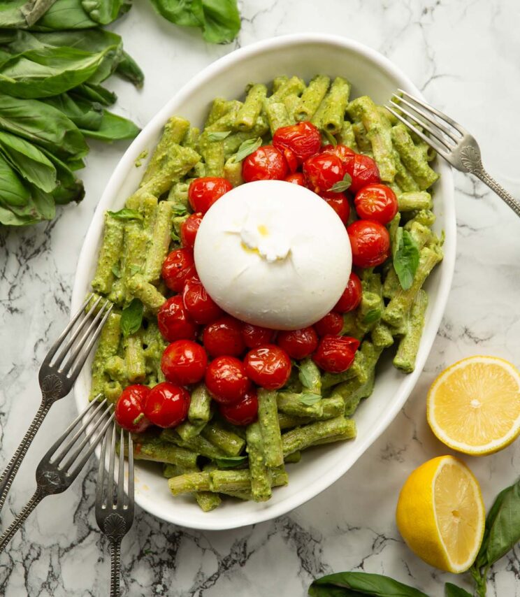 overhead shot of pistachio pesto pasta in large dish with tomatoes and burrata