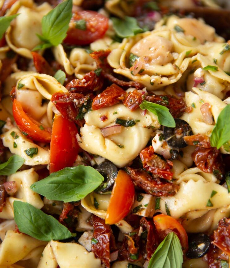 close up shot of sundried tomato tortellini salad garnished with basil