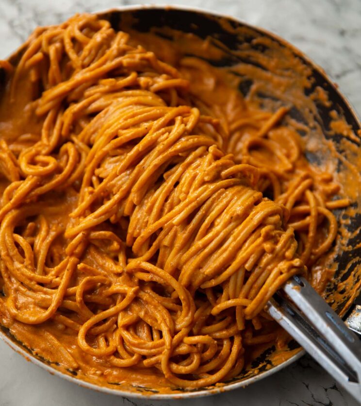 tomato cottage cheese pasta in large pan with tongs