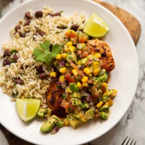 cajun chicken avocado corn salsa served with rice on small white plate