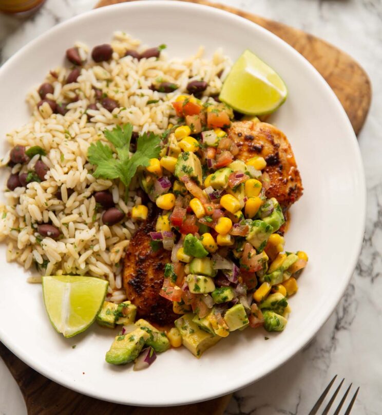 cajun chicken avocado corn salsa served with rice on small white plate