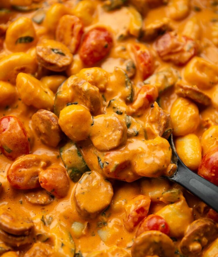 close up shot of black serving spoon digging into pan of creamy chorizo and gnocchi