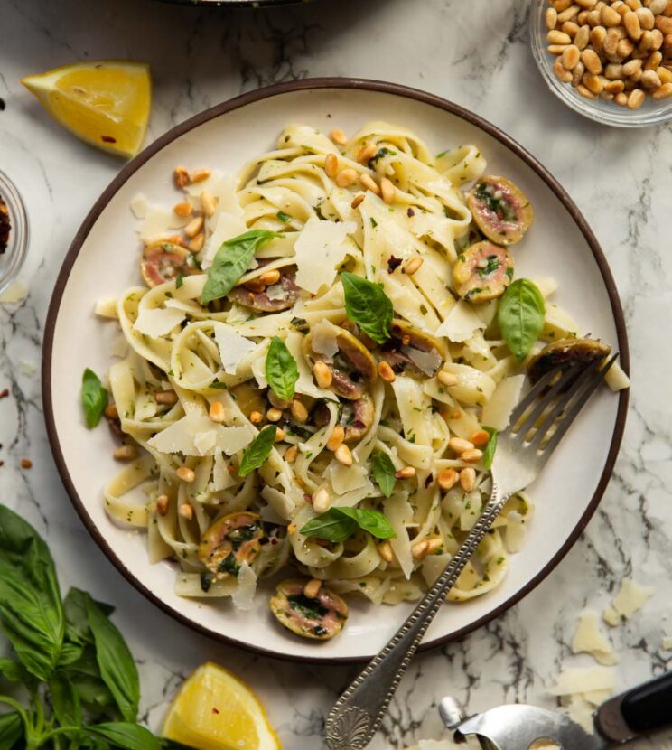 overhead shot of olive pasta on small white plate on marble background