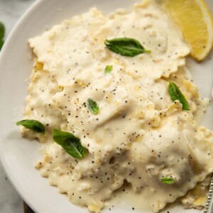 ravioli with lemon cream sauce served on small white plate garnished with basil