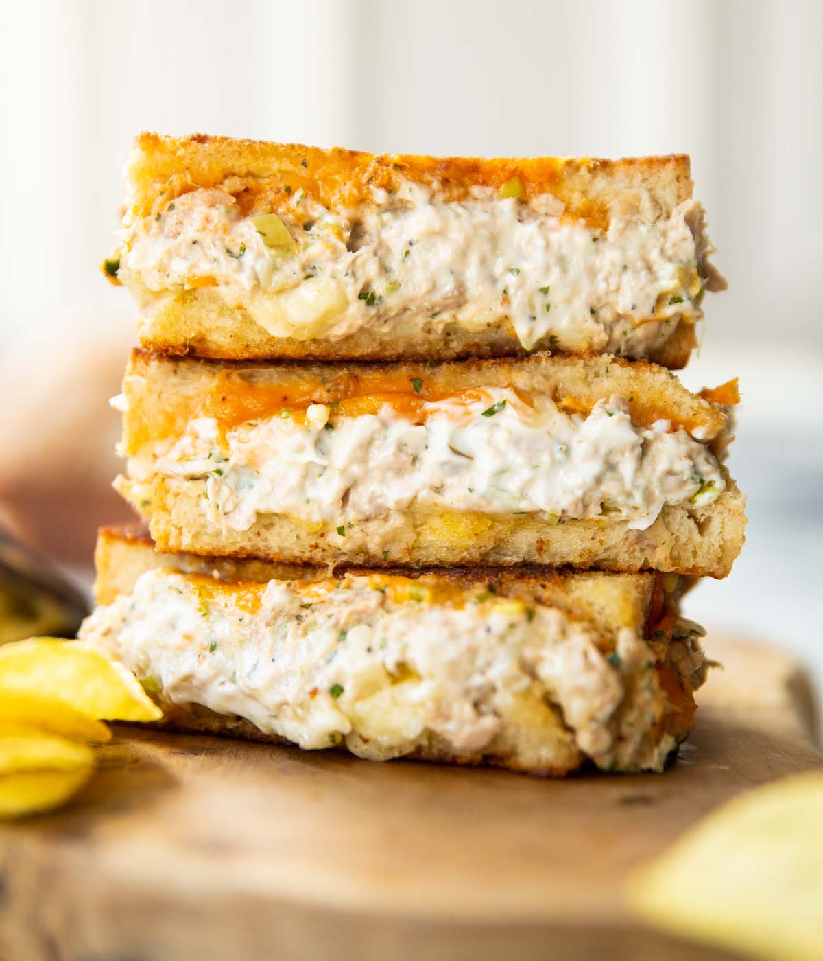 close up shot of 3 tuna melt halves stacked on each other on wooden board