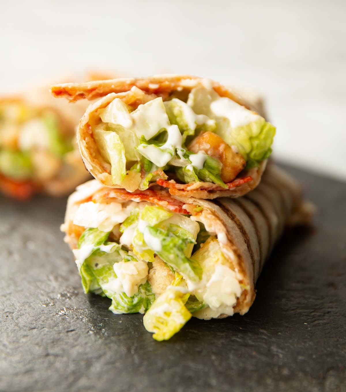 close up shot of caesar salad pepperoni wrap on slate
