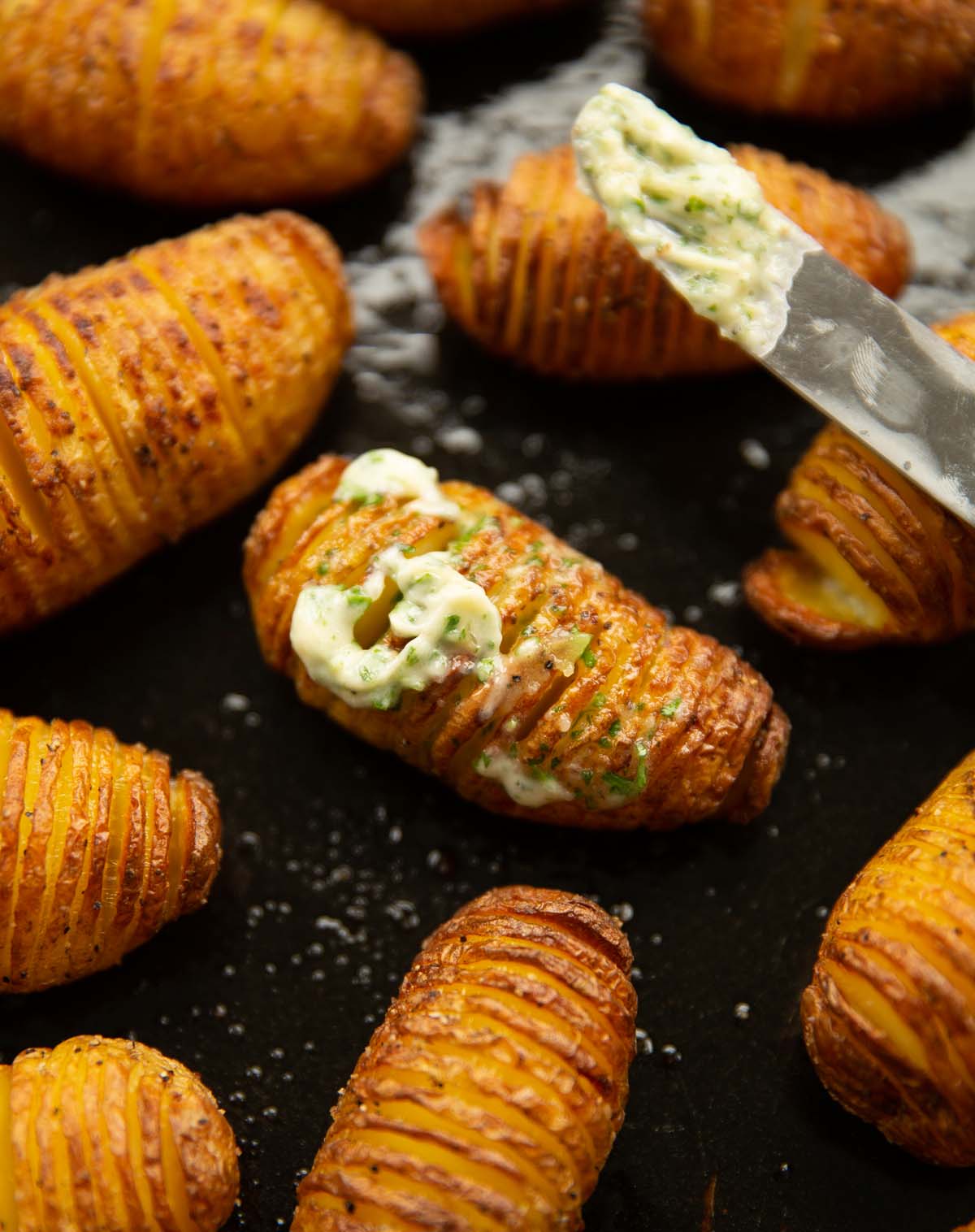 hasselback potatoes with garlic butter on black baking tray