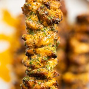 close up overhead shot of hand holding lemon butter chicken skewer