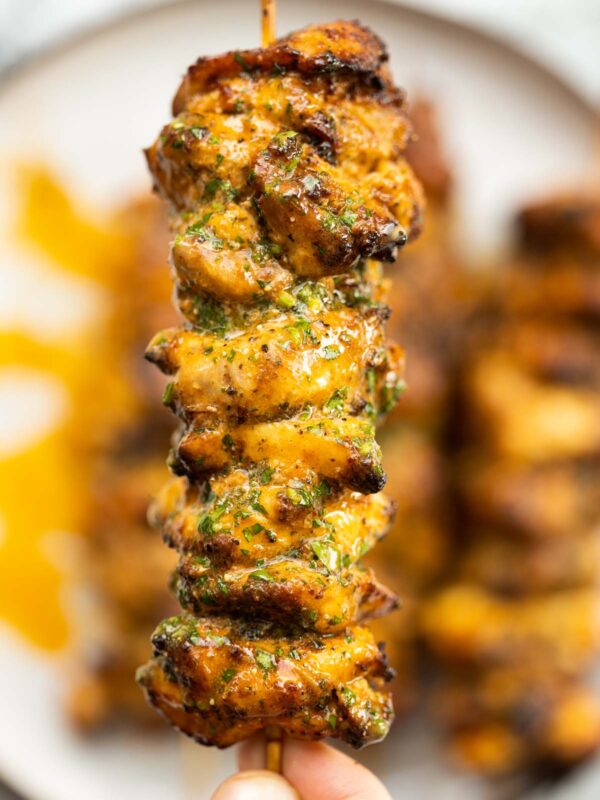 close up overhead shot of hand holding lemon butter chicken skewer