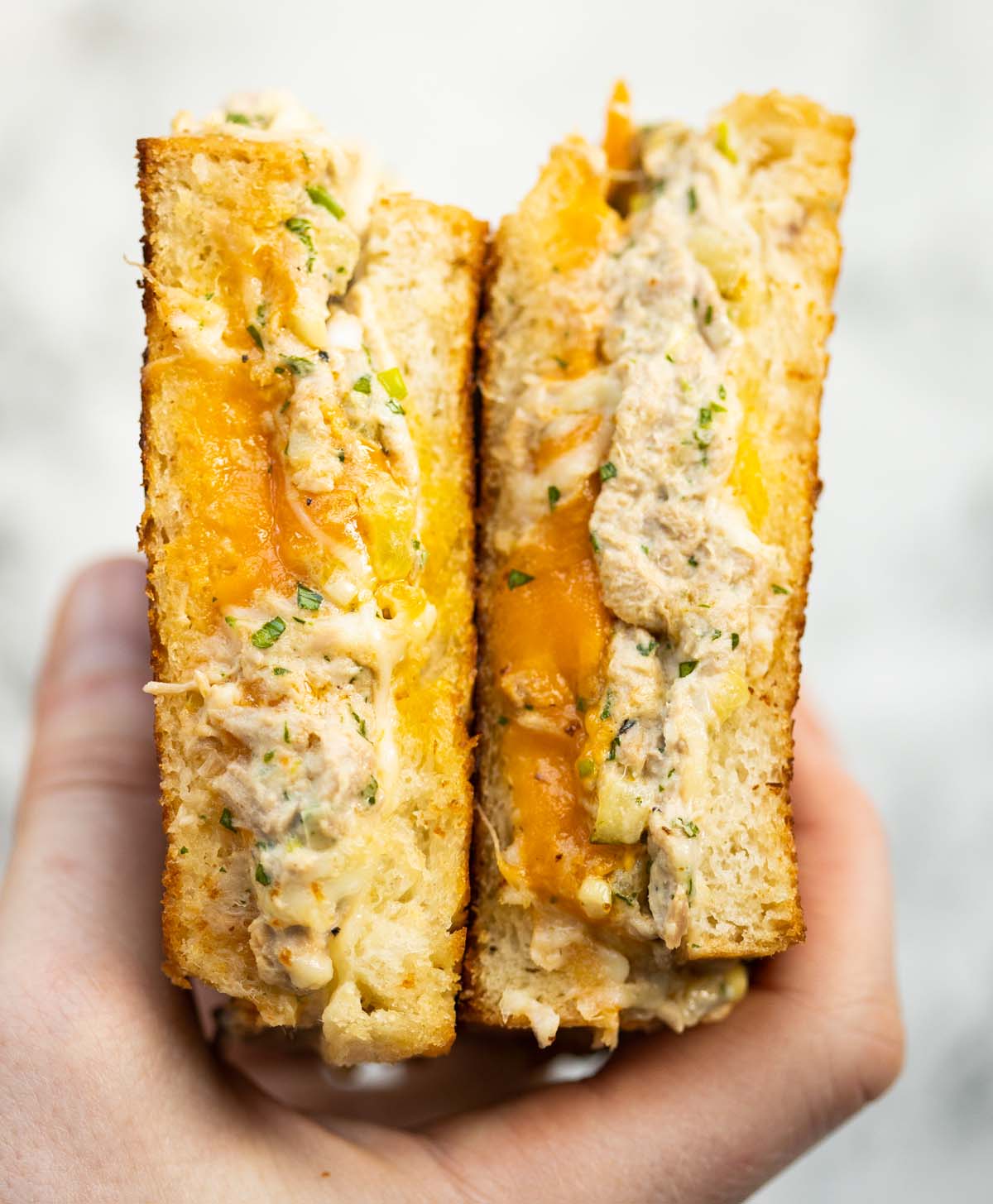 close up overhead shot of hand opening tuna melt showing filling