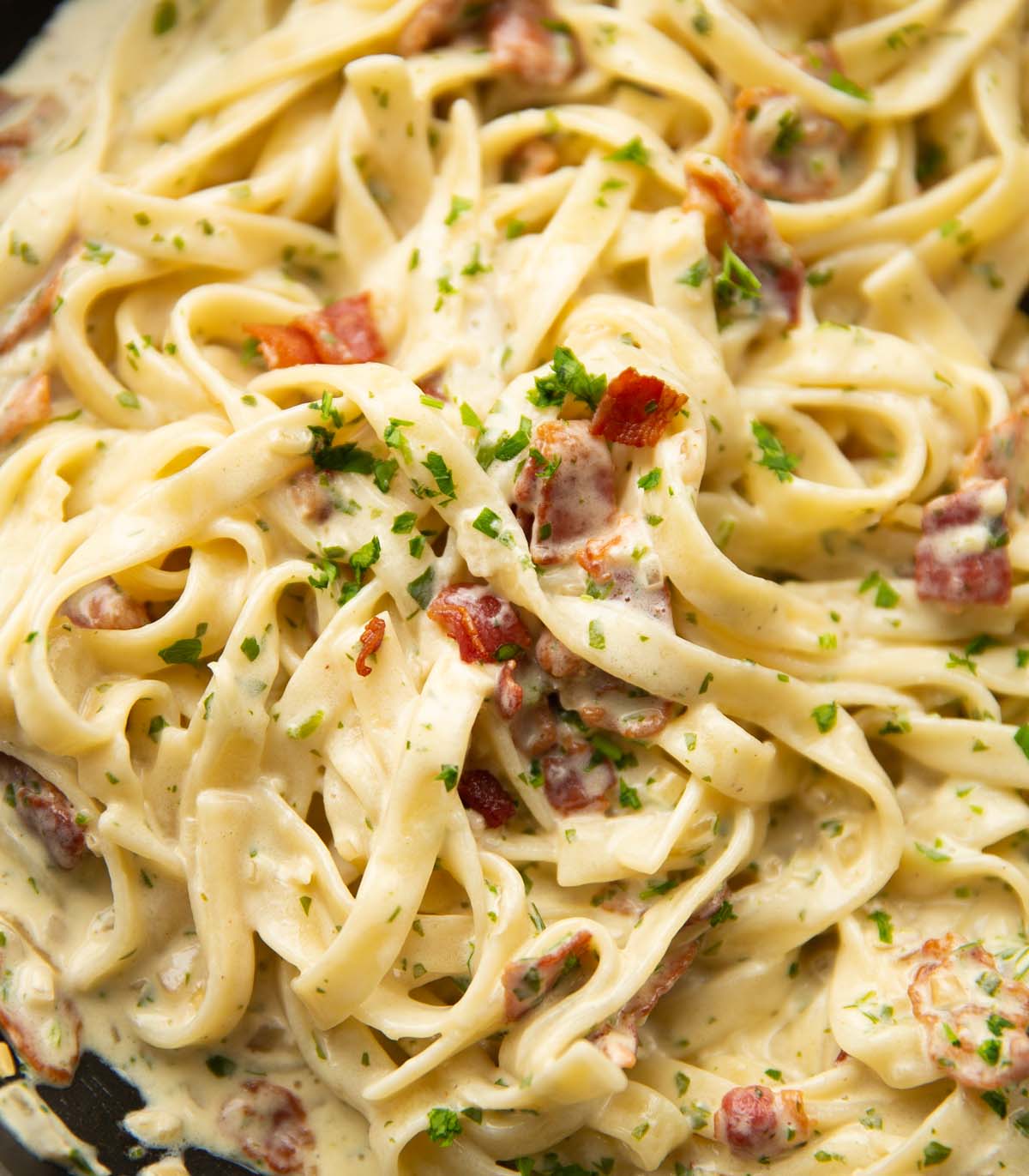 close up shot of creamy bacon pasta in large pan