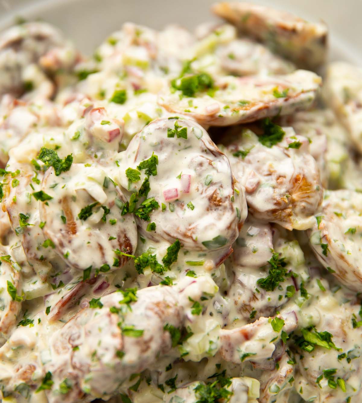 close up shot of crispy smashed potato salad in large white bowl
