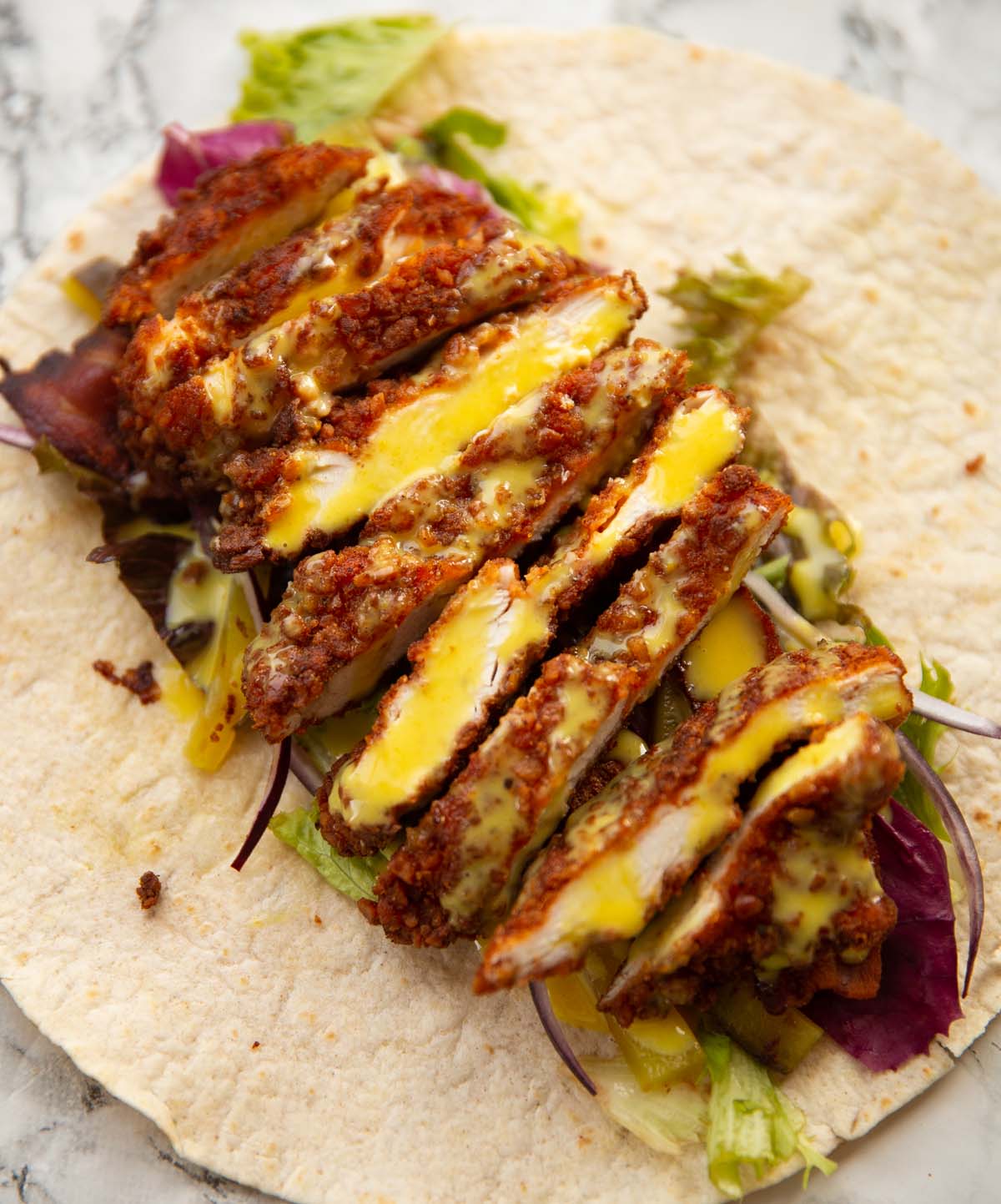 pretzel crusted chicken sliced in a wrap with salad