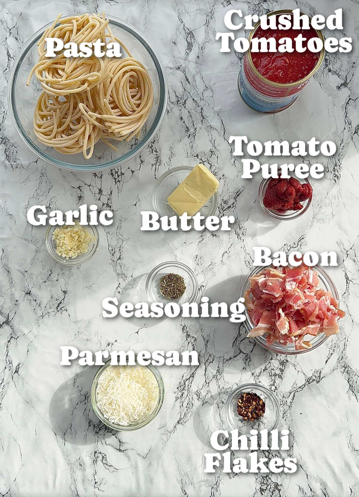 overhead shot of tomato bacon pasta ingredients with text labels