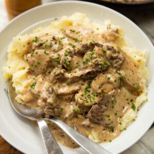 beef stroganoff served in white bowl with mashed potato