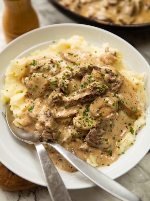 beef stroganoff served in white bowl with mashed potato