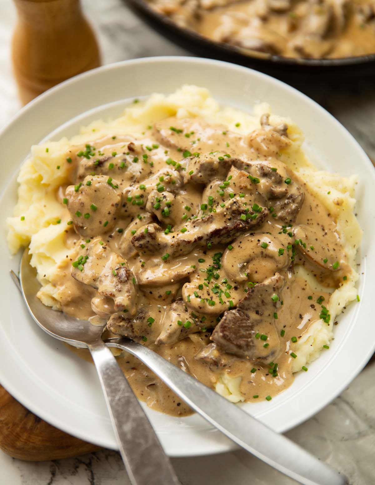 beef stroganoff served in white bowl with mashed potato