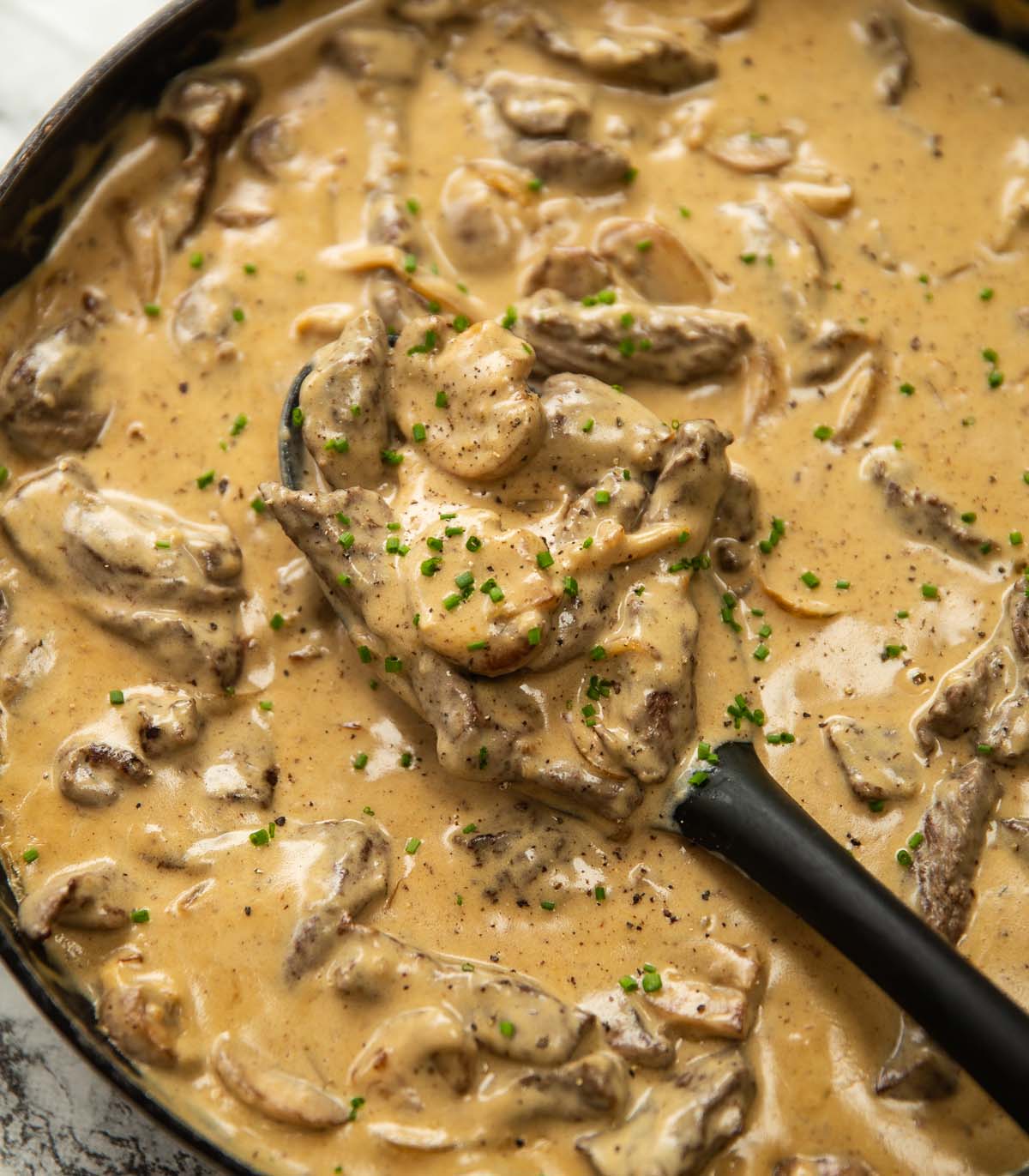 beef stroganoff in large pan with serving spoon