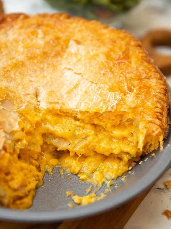 close up shot of cheese potato onion pie in dish with slice taken out