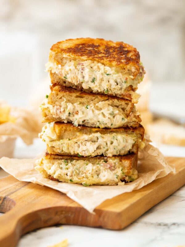 4 chicken melt halves stacked on each other on wooden board
