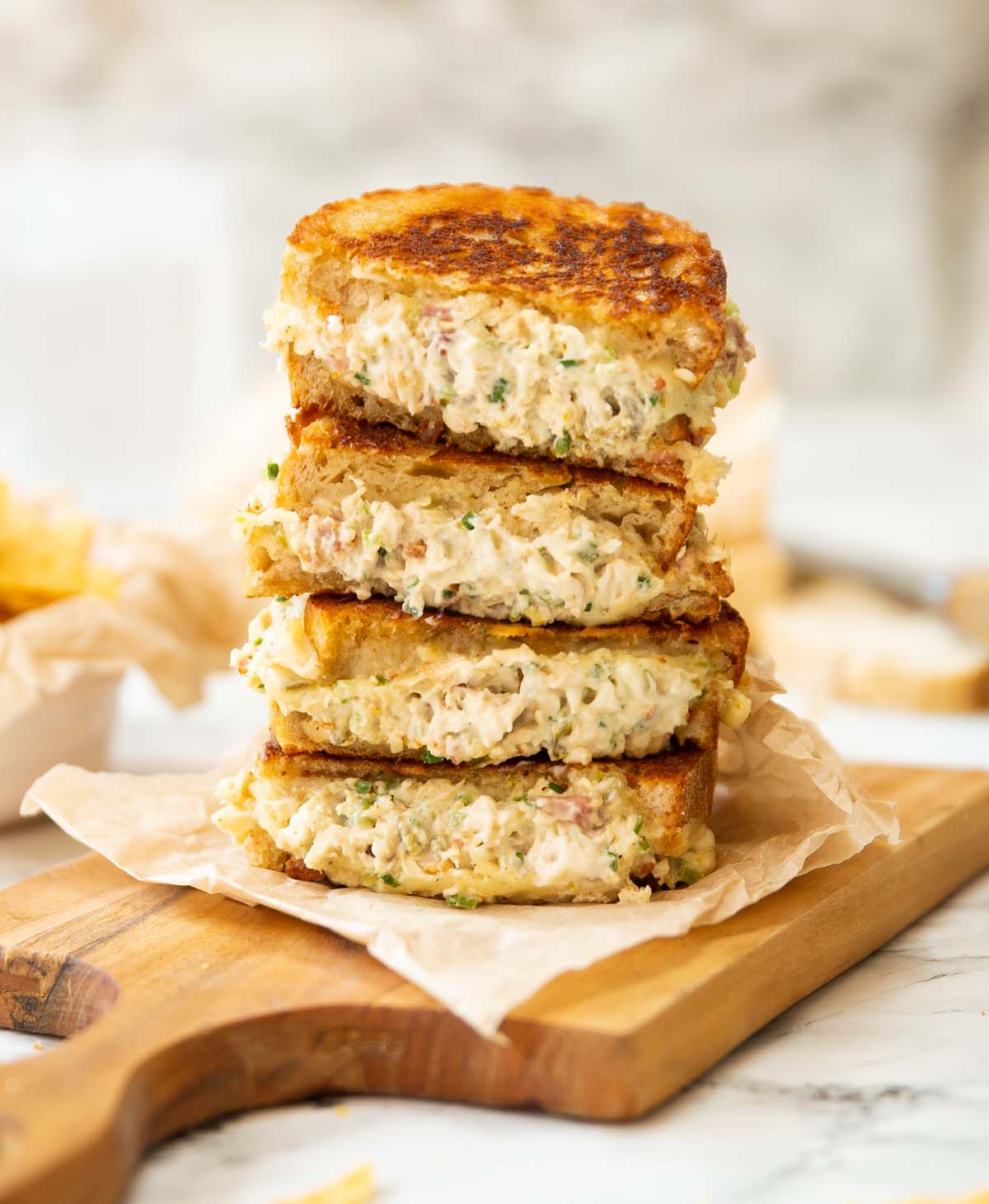4 chicken melt halves stacked on each other on wooden board