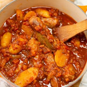 classic sausage casserole in dutch oven with wooden spoon