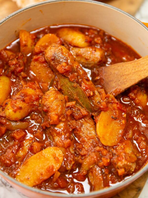 classic sausage casserole in dutch oven with wooden spoon