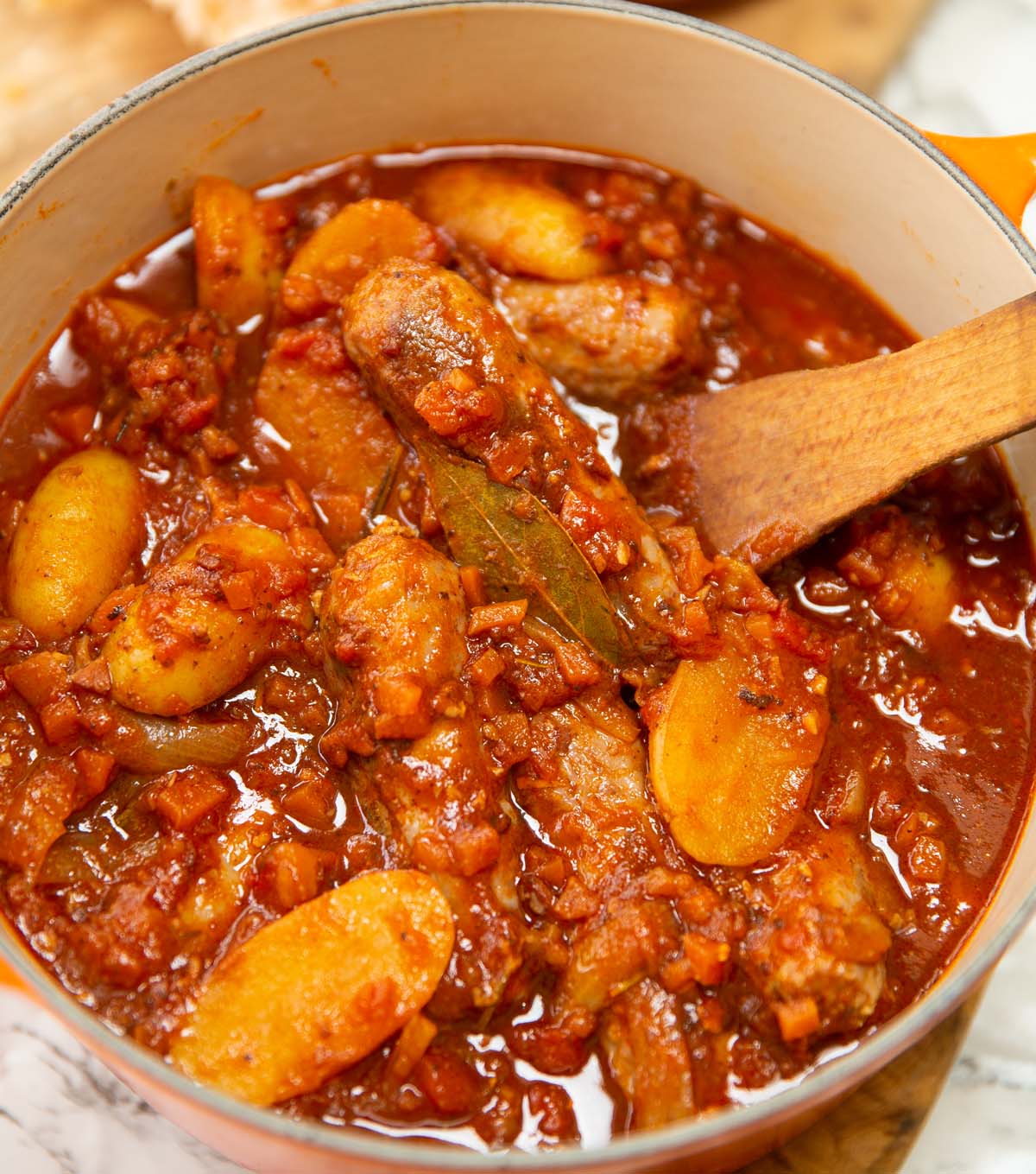 classic sausage casserole in dutch oven with wooden spoon
