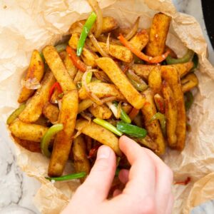 overhead shot of hand grabbing salt and chilli chips