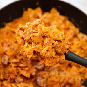 black serving spoon holding portion of spicy chorizo pasta